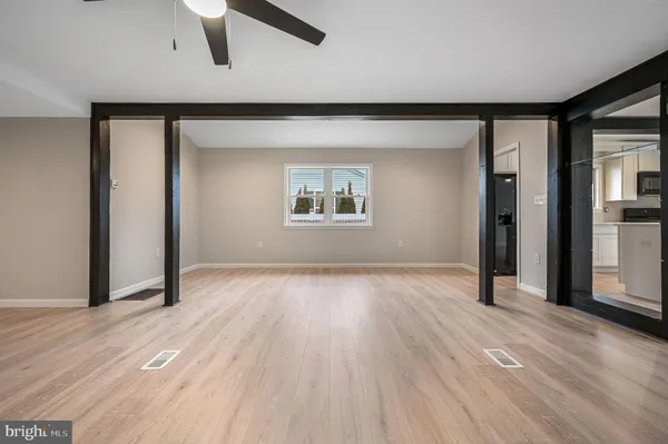 an empty room with wooden floor chandelier and windows