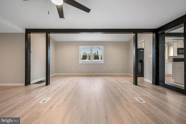 an empty room with wooden floor chandelier and windows