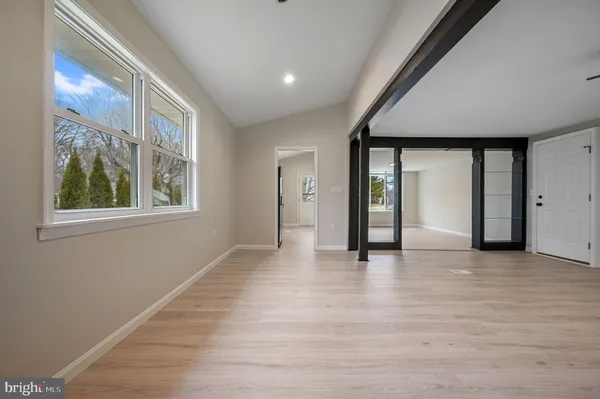 a view of an empty room with window and wooden floor