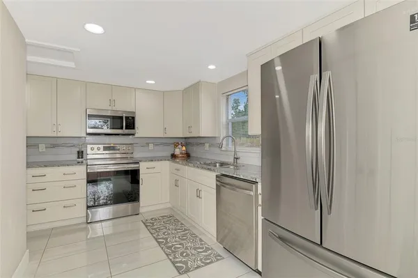 a kitchen with stainless steel appliances granite countertop a refrigerator and a stove top oven