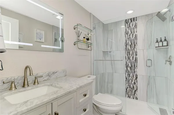 a bathroom with a granite countertop sink a toilet and shower