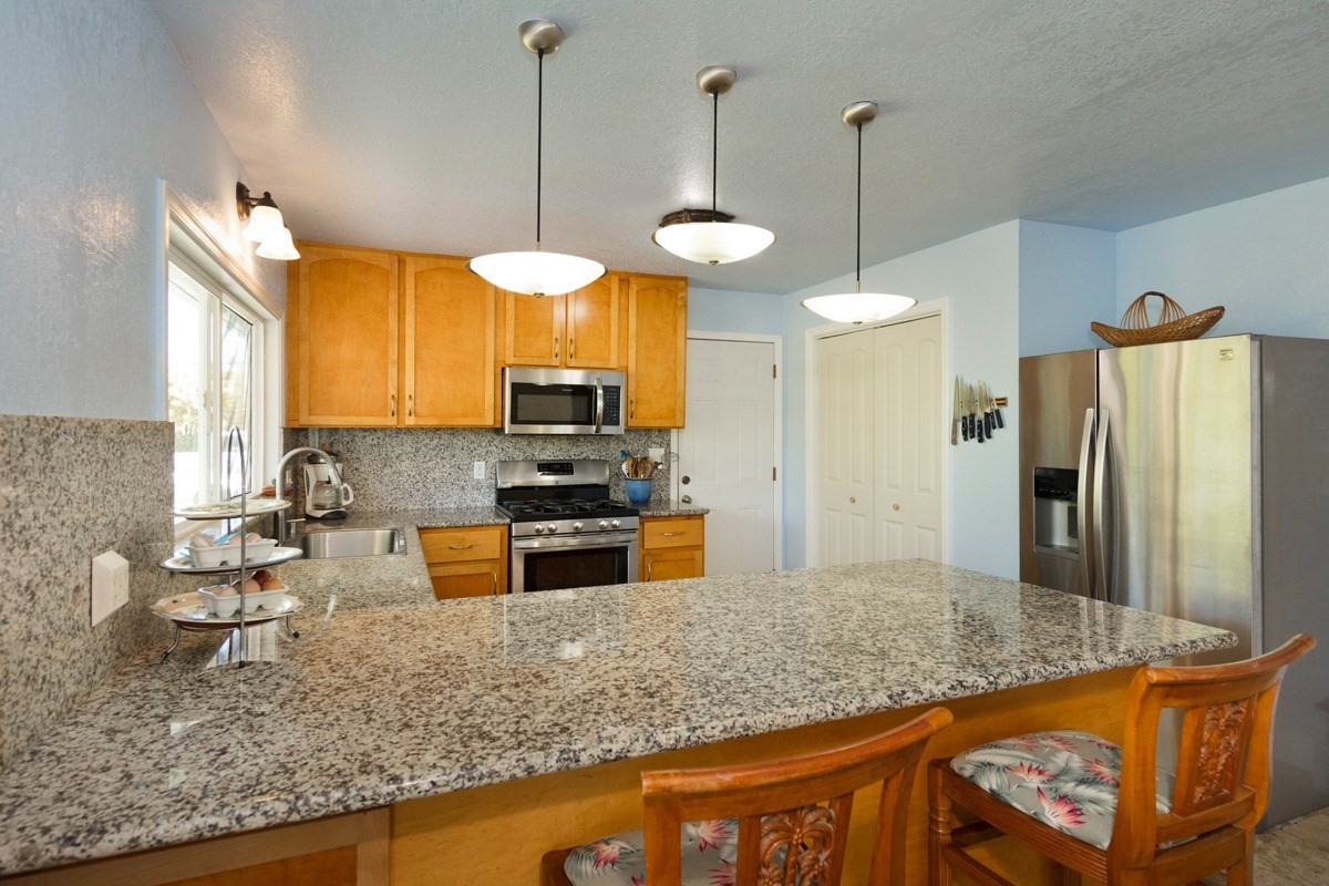 20 Hoaka Road Hilo, HI 96720 - Photo 5 of 30 a kitchen with stainless steel appliances granite countertop a sink a refrigerator and a wooden floor