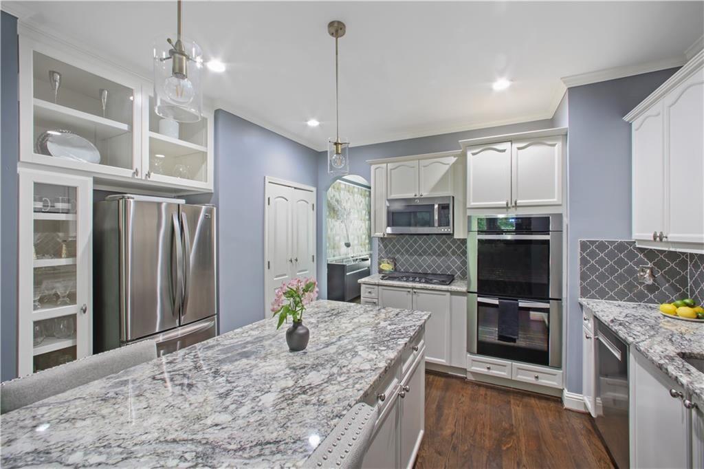 a large kitchen with granite countertop a large counter top appliances and cabinets
