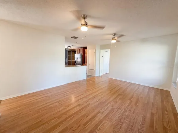 an empty room with wooden floor fan and window