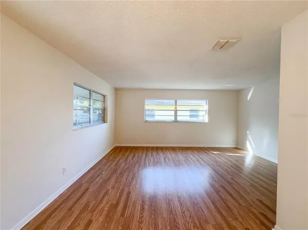a view of a big room with wooden floor and windows