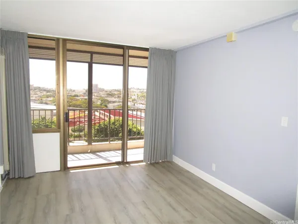 a view of an empty room with wooden floor and a window