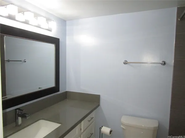 a bathroom with a granite countertop sink and a toilet
