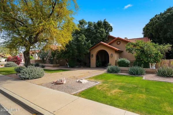 a front view of a house with garden and trees