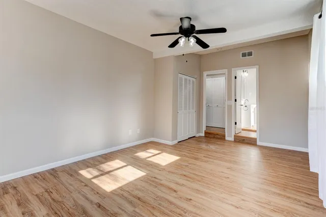 a view of empty room with wooden floor and ceiling fan