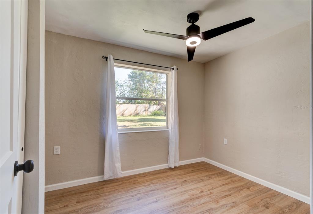 13 Highridge Road Daytona Beach, FL 32117 - Photo 18 of 27 an empty room with wooden floor chandelier fan and windows