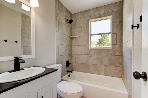 a bathroom with a bathtub shower sink vanity and toilet