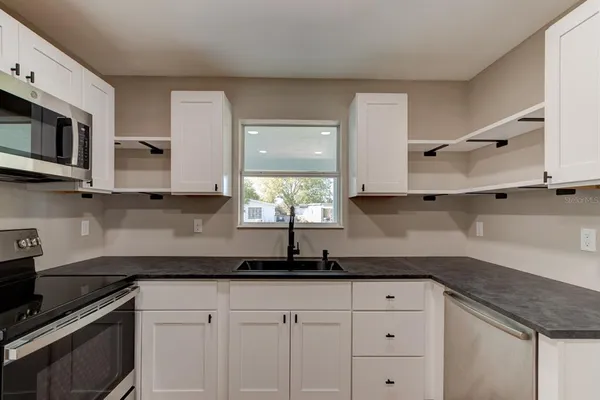 a kitchen with stainless steel appliances granite countertop white cabinets granite counter tops and a wooden floors