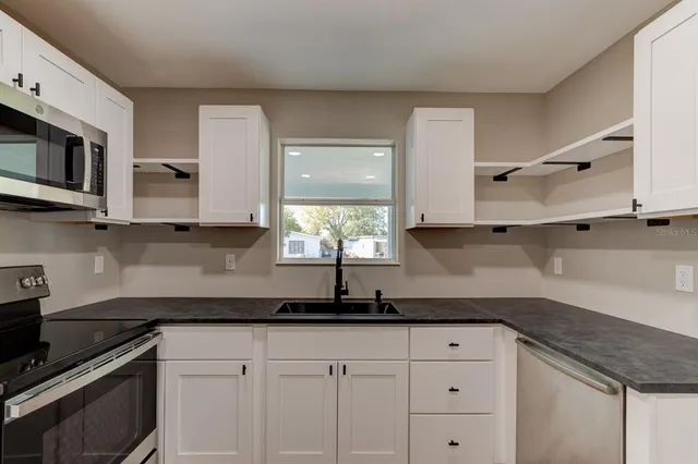 a kitchen with stainless steel appliances granite countertop white cabinets granite counter tops and a wooden floors
