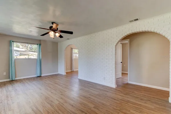 a view of an empty room with wooden floor and a window