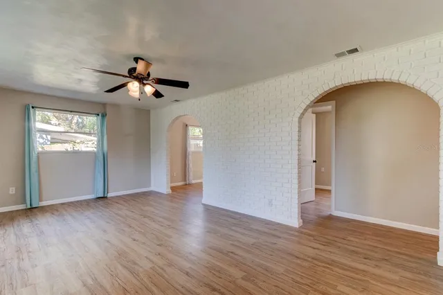 a view of an empty room with wooden floor and a window