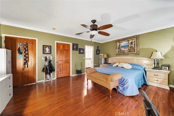 a large bedroom with wooden floor and ceiling fan