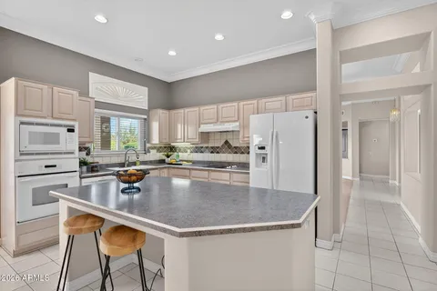 a kitchen with stainless steel appliances granite countertop a stove a refrigerator a sink a dining table and chairs