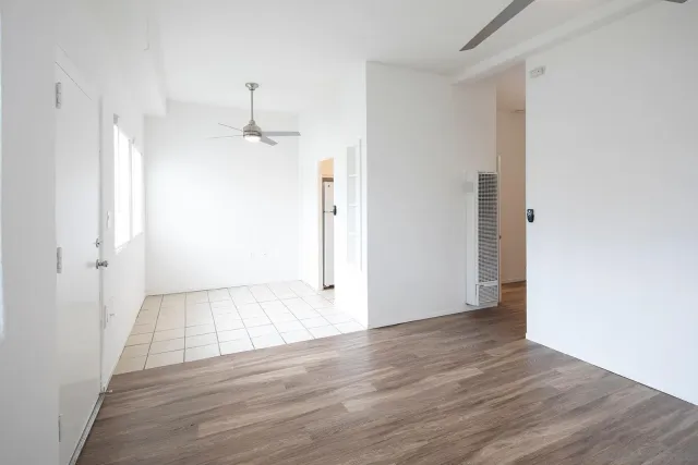 a view of a room with wooden floor a ceiling fan and window