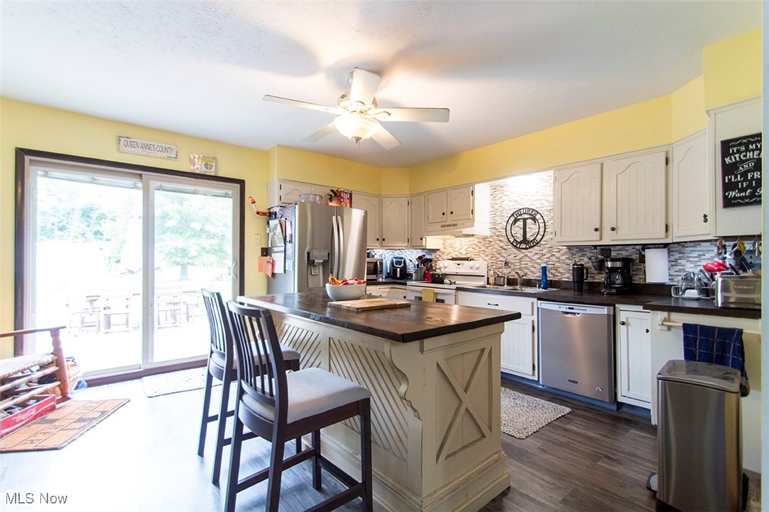 8559 Crow Road Litchfield, OH 44253 - Photo 5 of 27 Kitchen with stainless steel appliances, a kitchen island, backsplash, dark hardwood / wood-style flooring, and ceiling fan