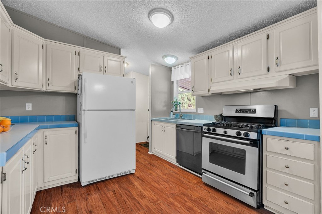 20401 Soledad Canyon Road, Unit 139 Canyon Country, CA 91351 - Photo 8 of 35 a kitchen with cabinets appliances wooden floor and stainless steel appliances