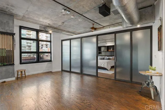 a view of an empty room with a window and wooden floor