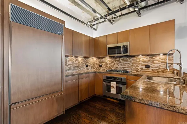 a room with stainless steel appliances dining table wooden floor and window