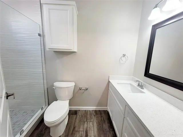 a bathroom with a granite countertop toilet a sink and a mirror