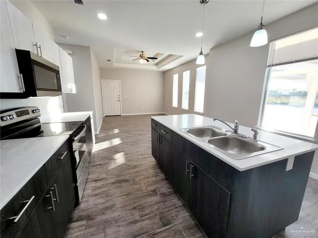 a kitchen with kitchen island a sink appliances and a counter top space