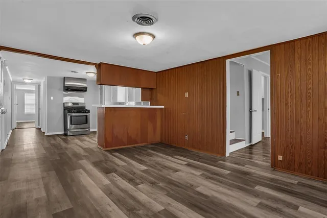 an empty room with wooden floor and kitchen view
