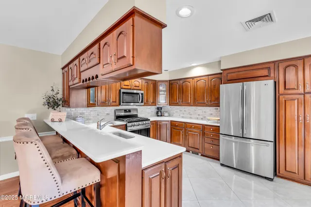 a kitchen with stainless steel appliances granite countertop a refrigerator a stove a sink dishwasher and white cabinets with wooden floor