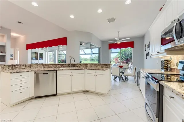 a kitchen with stainless steel appliances kitchen island granite countertop a stove a sink and a refrigerator