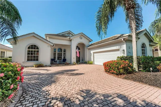 a front view of a house with a garden and trees