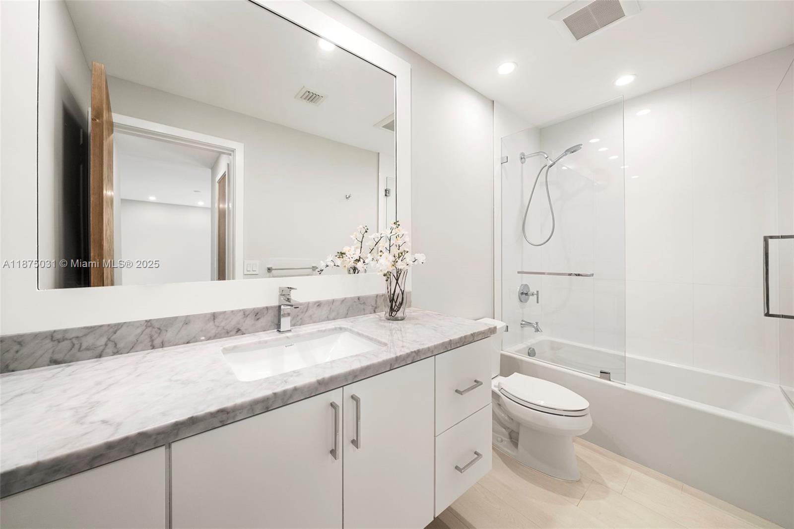 4380 Lake Road Miami, FL 33137 - Photo 25 of 61 a bathroom with a granite countertop sink a toilet and a large mirror