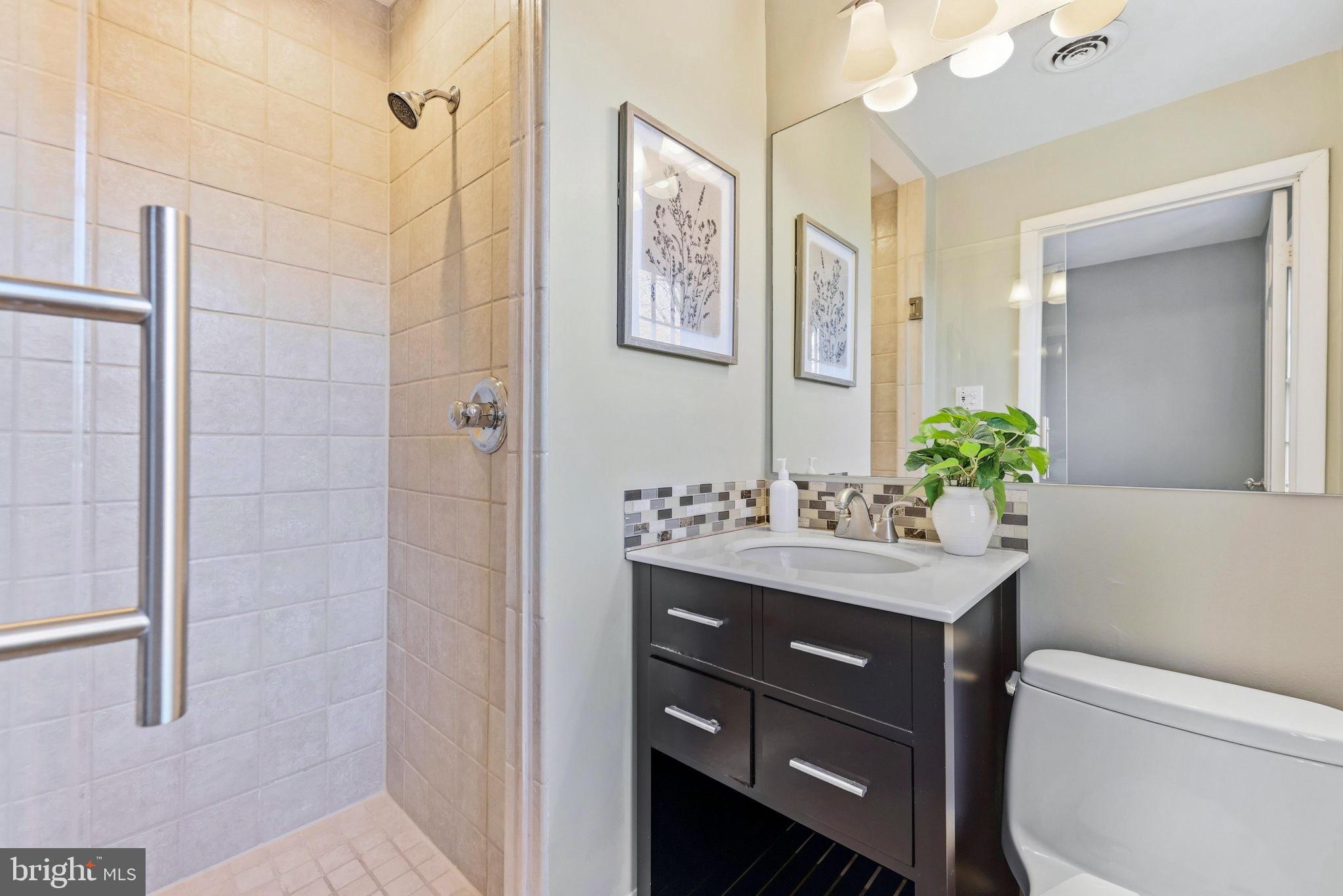 9101 Warfield Road Gaithersburg, MD 20882 - Photo 26 of 44 a bathroom with a granite countertop sink a toilet and a mirror