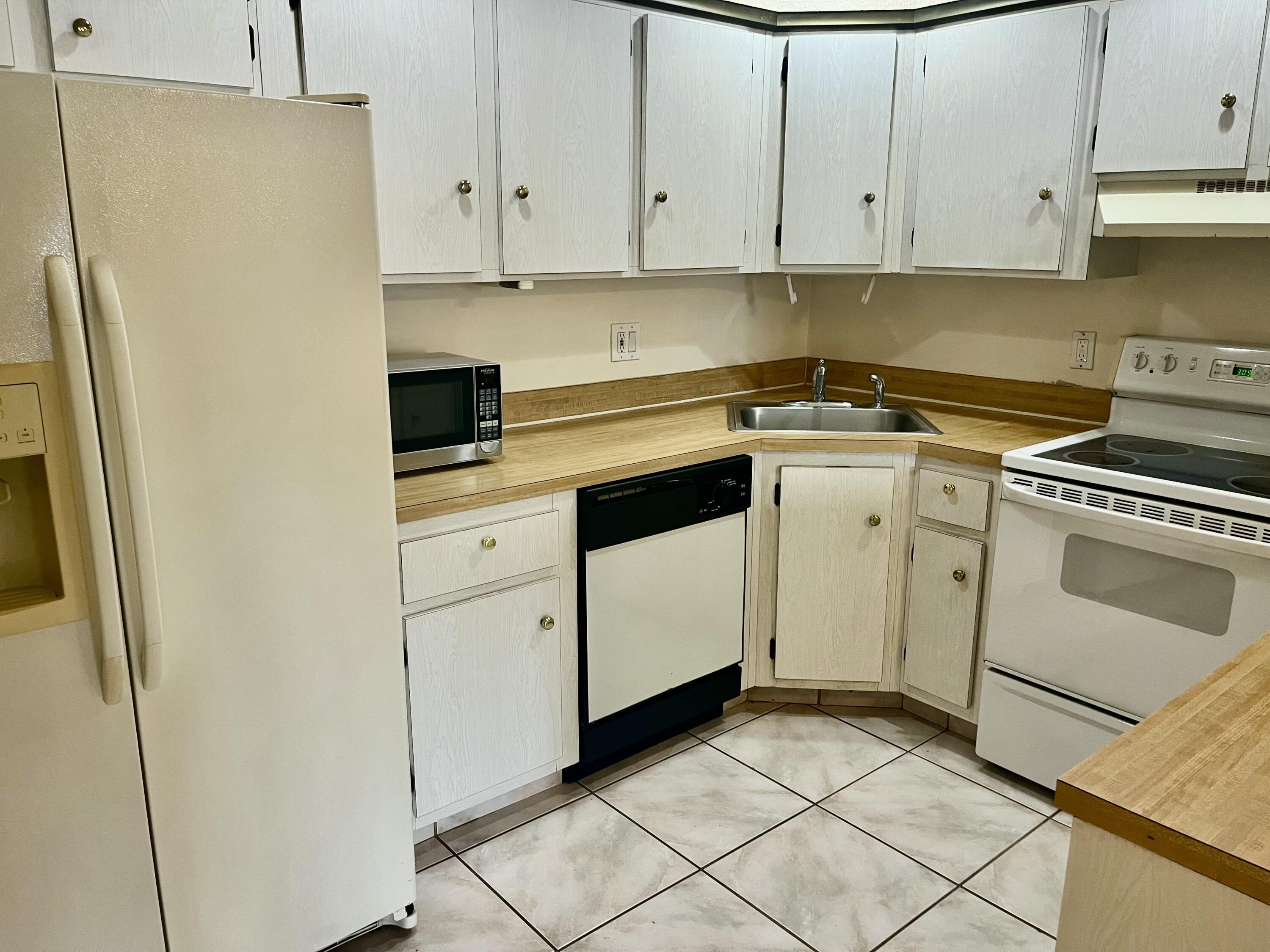 536 Shady Pine Way, Unit C2 Greenacres, FL 33415 - Photo 12 of 28 a kitchen with white cabinets and white appliances