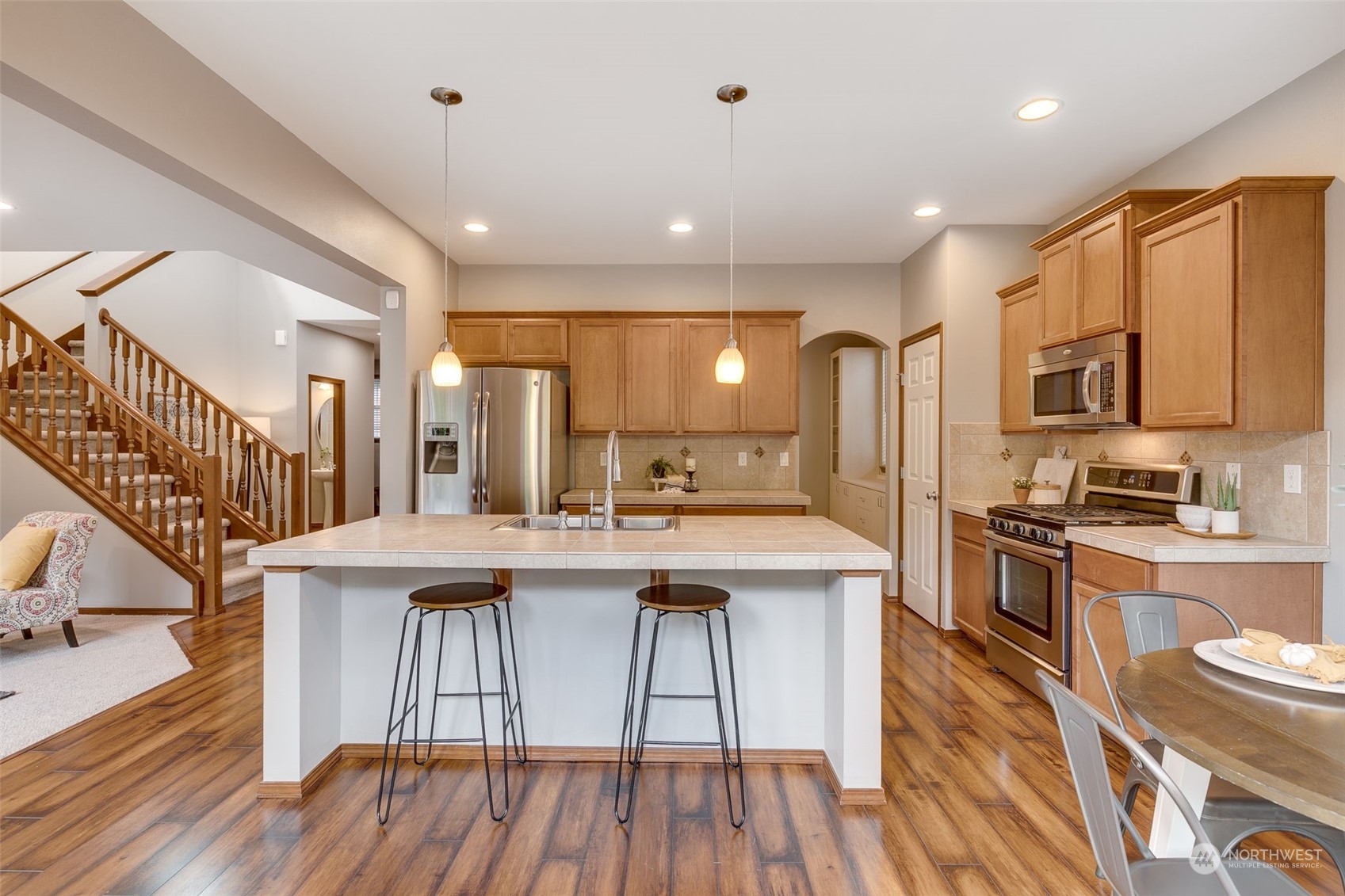 22917 42nd Drive Southeast Bothell, WA 98021 - Photo 6 of 36 a kitchen with stainless steel appliances granite countertop a kitchen island hardwood floor sink stove dining table and chairs