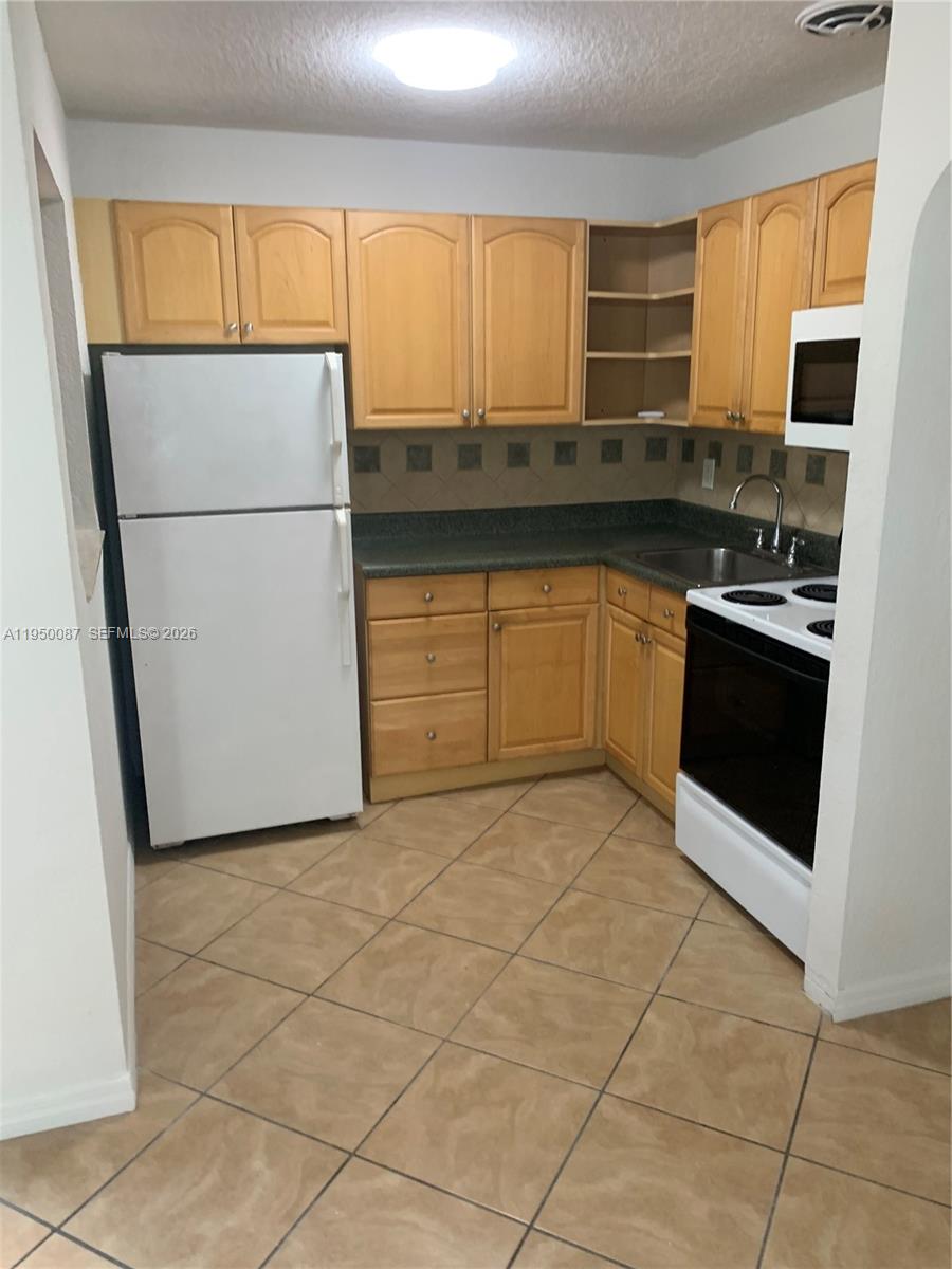 5616 Arthur Street, Unit NORTH Hollywood, FL 33021 - Photo 7 of 16 a kitchen with stainless steel appliances granite countertop a stove a sink and a refrigerator