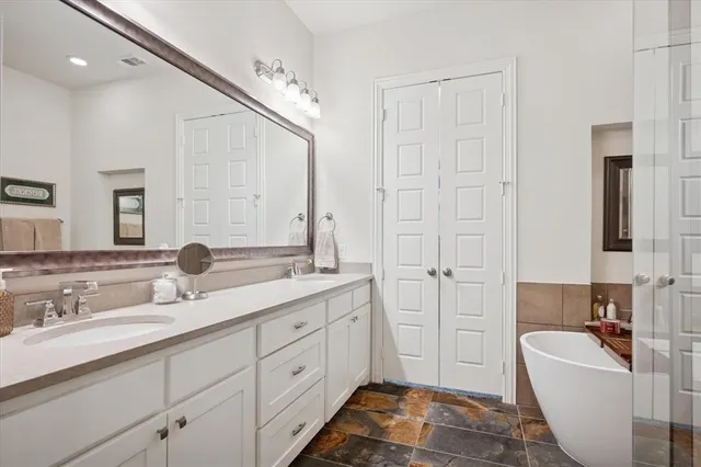 a spacious bathroom with a double vanity sink mirror and bathtub
