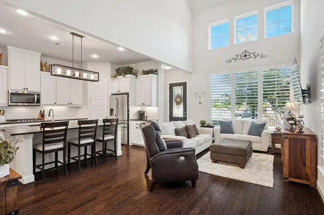 a large living room with stainless steel appliances kitchen island granite countertop wooden floor a dining table and chairs