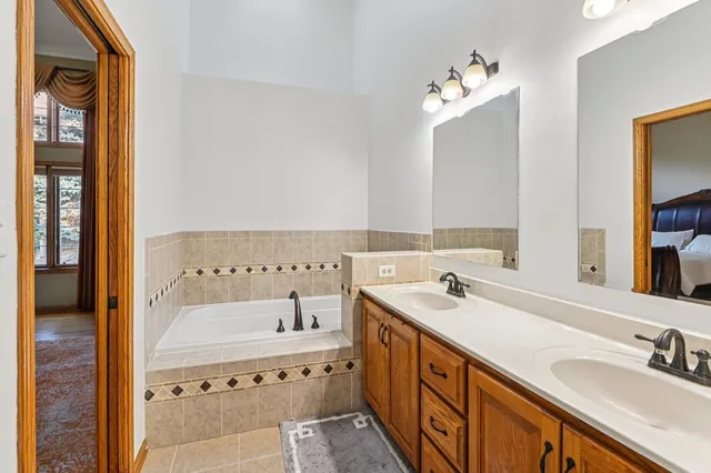 a bathroom with a sink vanity granite tub and a mirror