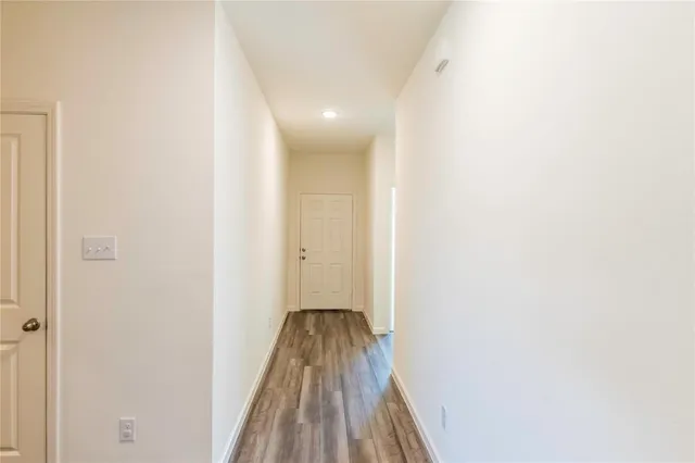 a view of a hallway with a white door and wooden floor