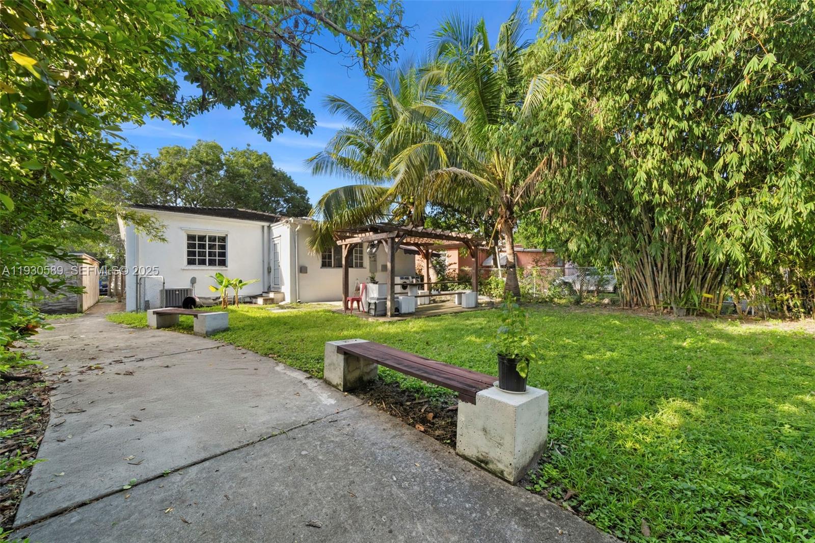 555 Northeast 73rd Street Miami, FL 33138 - Photo 26 of 32 a view of a white house with a yard and table and chairs under an umbrella