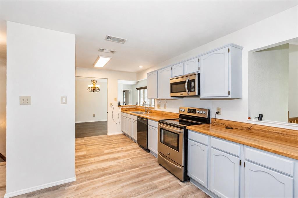 6545 Los Rios Drive Mesquite, TX 75150 - Photo 2 of 9 Kitchen featuring wood-finish flooring, light blue cabinetry, and wood-finish countertops