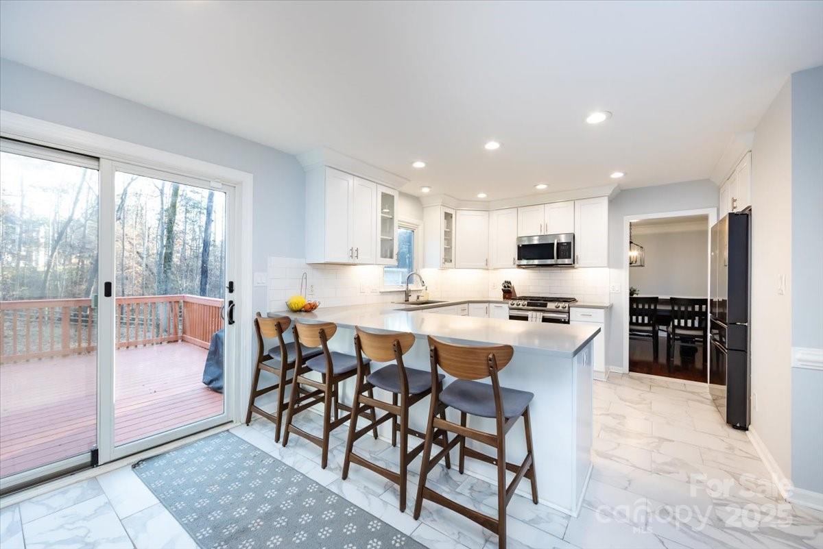 10937 Back Ridge Road Charlotte, NC 28277 - Photo 14 of 45 a kitchen with stainless steel appliances kitchen island granite countertop a table and chairs in it