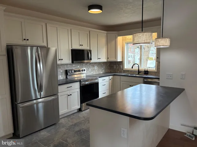 a kitchen with stainless steel appliances granite countertop a refrigerator a sink a stove and a refrigerator