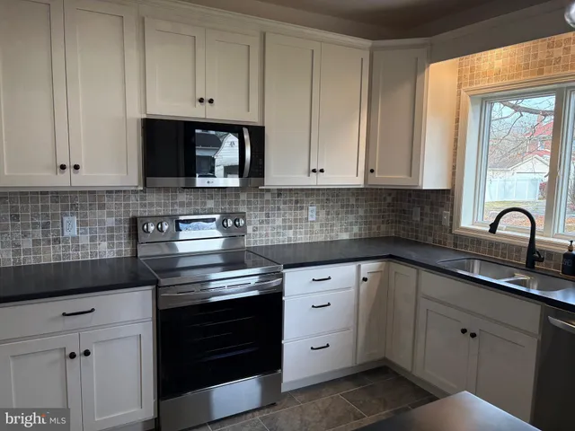 a kitchen with white cabinets and appliances