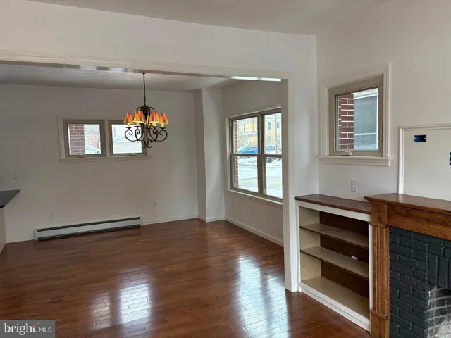 an empty room with wooden floor cabinet and windows