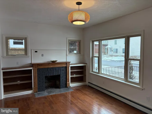 a view of an empty room with a window and fireplace