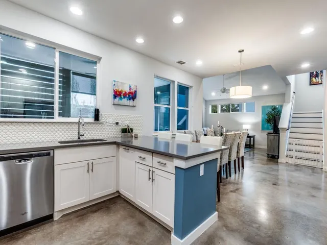 a kitchen with lots of counter space sink and view of living room