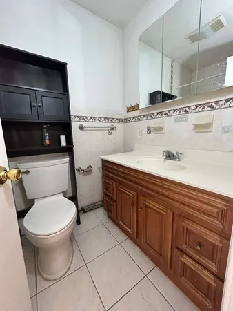 a bathroom with a granite countertop toilet sink and mirror